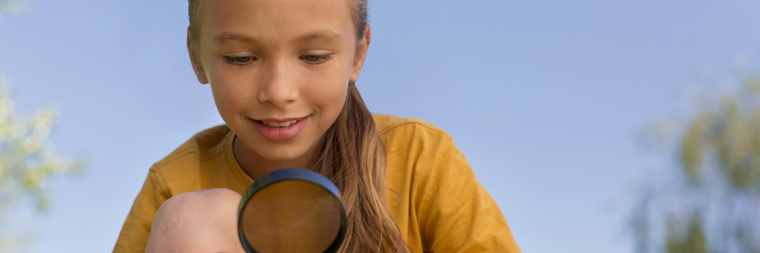 bambina che osserva una foglia con una lente nella mano