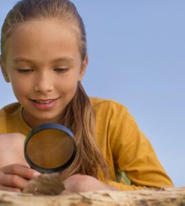 bambina che osserva una foglia con una lente nella mano