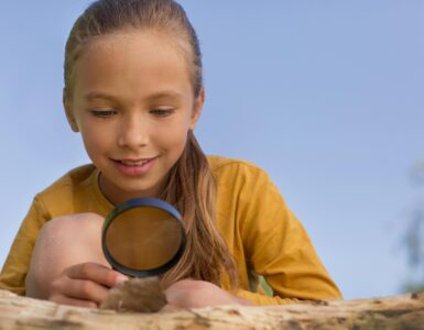 bambina che osserva una foglia con una lente nella mano