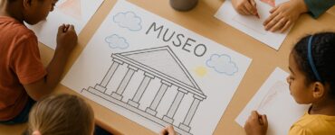 quattro bambini disegnano con i pastelli su un foglio di carta ciascuno la propria idea di museo